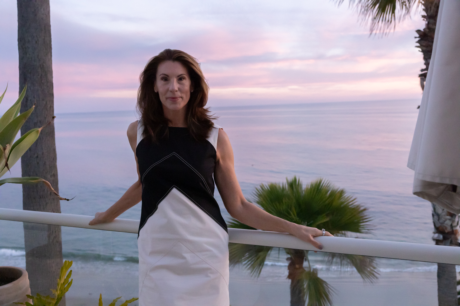 Alicia Gilbert on a balcony overlooking the ocean at sunset
